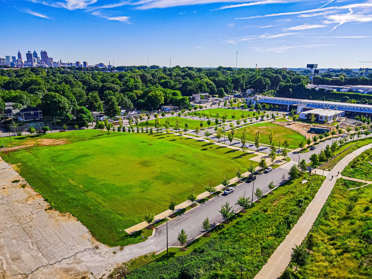 A large grassy field is shown to the side of the paved Atlanta Beltline trail.