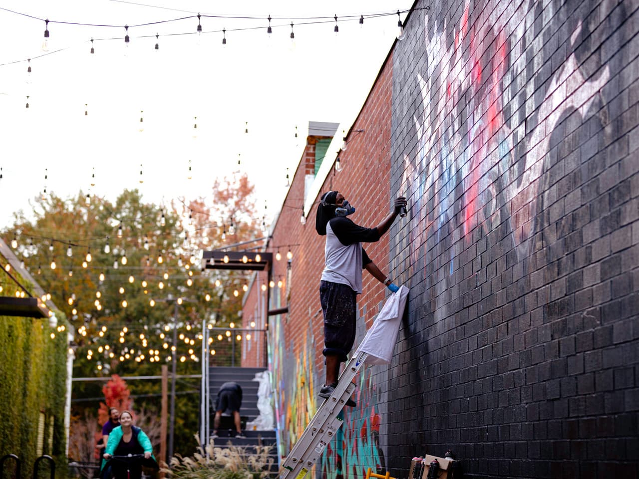 A man paints a brick wall using spray paint.