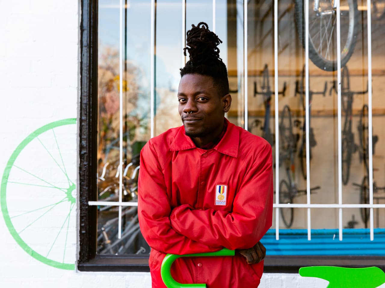 A man in a red sweatshirt stands in front of a bicycle store.