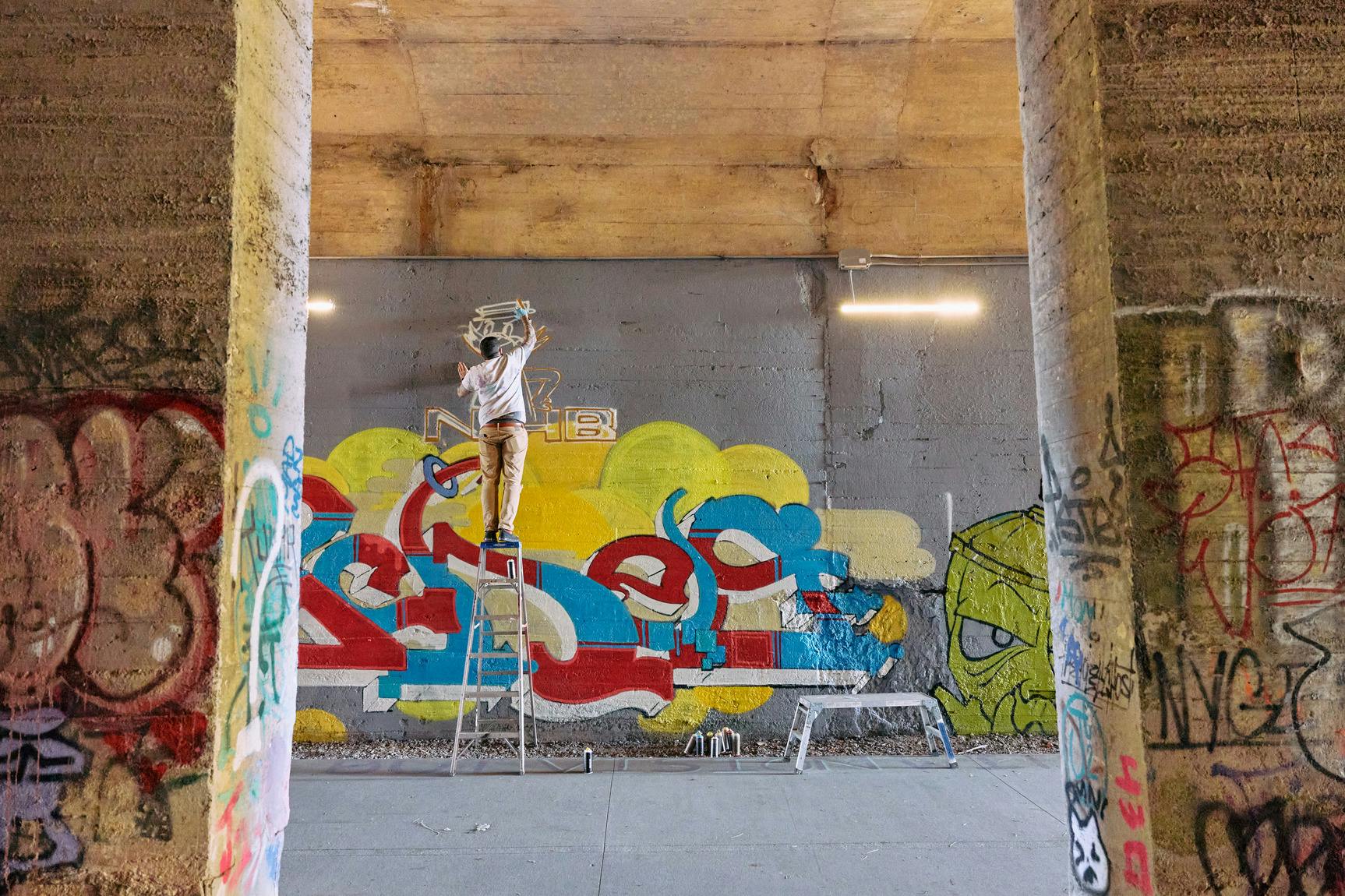 Man stylewriting in Lee + Murphy tunnel with views of bridge columns