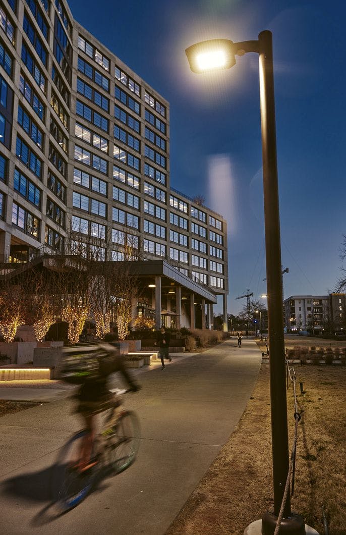 A blurry person bikes past buildings and lights at night.